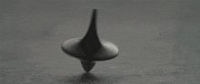 a black and white photo of a spinning top on a black surface