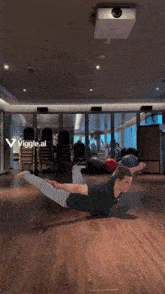 a man in a green shirt is doing a yoga pose in a gym with the words viggle.ai visible
