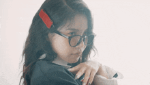 a woman wearing glasses has a red hair clip on her head
