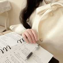 a woman in a white coat is holding a pen over a notebook that says ' x ' on it