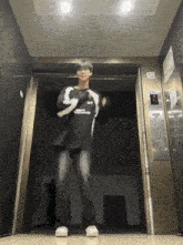 a person standing in an elevator wearing a black shirt that says ' sss ' on it