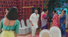 a man in a white shirt is dancing in a room surrounded by people .