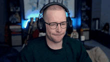 a man wearing headphones and glasses is sitting in front of a computer screen .