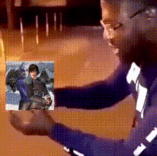 a man in a purple shirt holds a picture of a person