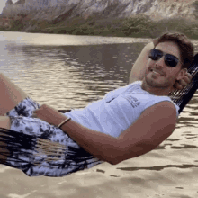a man wearing sunglasses is laying in a hammock with a shirt that says columbia on it