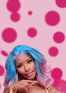 a woman with blue and pink hair is standing in front of a pink background .