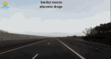 a car is driving down a highway with the words bardzo mocno placesz drogo behind it