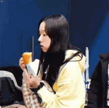 a young girl in a yellow hoodie is eating a sandwich .