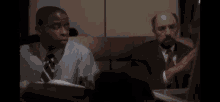 two men are sitting on a couch looking at a laptop computer .