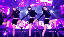 three women are dancing on a stage in front of a large screen .
