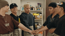 a group of men are putting their hands together in front of a shelf that says shot break