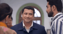 a group of men are standing next to each other in a room and smiling at each other .