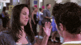 a man and a woman are waving at each other in a hallway