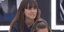 a woman with long hair is making a funny face while sitting next to a little girl .