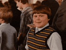 a boy wearing a striped vest is standing in a crowd
