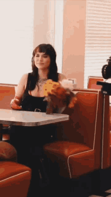 a woman is sitting at a table in a diner holding flowers