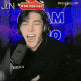a man wearing headphones is screaming into a microphone with t98 strong written on the bottom right