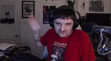 a man wearing headphones and a red shirt is sitting at a desk in a room .