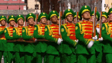 a group of men in green and red uniforms marching in a line