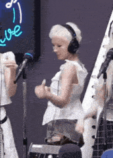 a woman wearing headphones stands in front of a microphone and a sign that says love