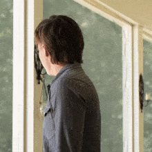 a man in a striped shirt is looking out of a window