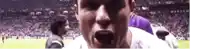 a man in a white shirt is screaming in a stadium