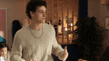 a young man in a white sweater is dancing in a room