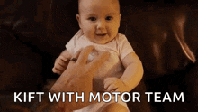 a baby is sitting on a couch with a pacifier in his mouth and a person is holding him .