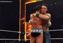 two men hugging in a wrestling ring with the hashtag thekamdreesen behind them