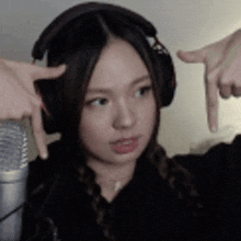 a woman wearing headphones is making a funny face while pointing at herself .