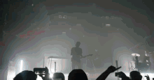 a man is playing a guitar on a stage in front of a crowd of people .
