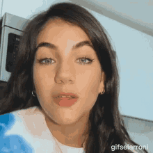 a close up of a girl 's face with a microwave in the background