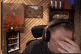 a man wearing headphones is covering his face in front of a television .