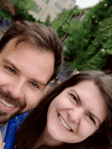 a man and a woman are posing for a picture and smiling for the camera