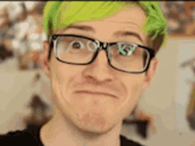 a man with green hair and glasses making a funny face .
