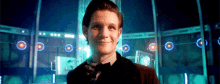 a man in a suit and tie is smiling in front of a building with a lot of lights .