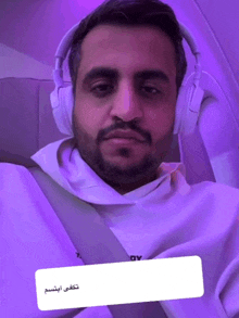 a man wearing headphones and a white hoodie with a purple background