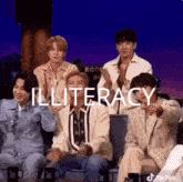 a group of young men are sitting around a table with the word illiteracy written on it .