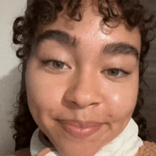 a close up of a woman 's face with curly hair and green eyes .