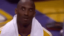 kobe bryant is wearing a towel around his neck and looking at the camera .