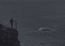 a man stands on a cliff overlooking the ocean