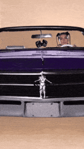 a woman is driving a purple mustang with a star wars emblem on the front bumper