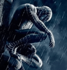 a man in a spiderman costume sits in the rain