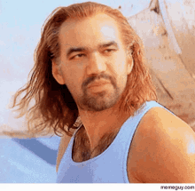 a man with long hair and a beard is wearing a tank top