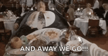 a very fat man is laying on a table with plates of food and says `` and away we go '' .