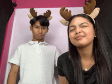 a boy and a girl wearing reindeer antlers are posing for a picture