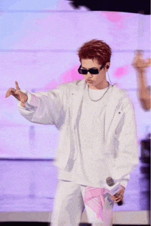 a man wearing sunglasses and a white shirt holds a microphone in his hand