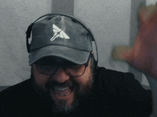 a man with a beard wearing a hat with a white x on it