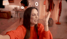 a woman in a red shirt is taking a selfie in a living room .