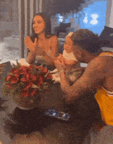 a man in a yellow shirt holds a baby while a woman applauds